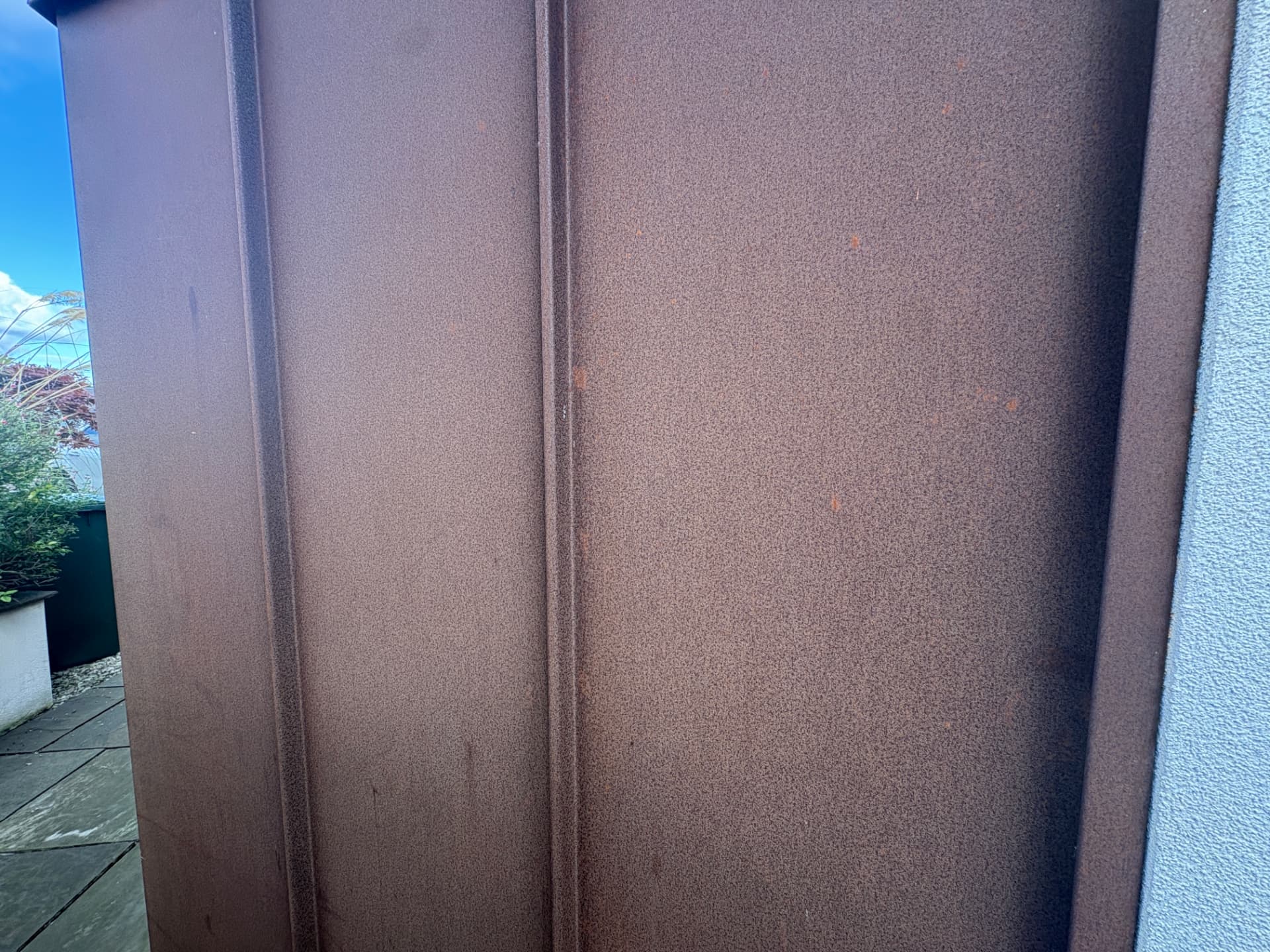 Corten weathering steel planter with folded seams and a rich rust patina on a garden terrace